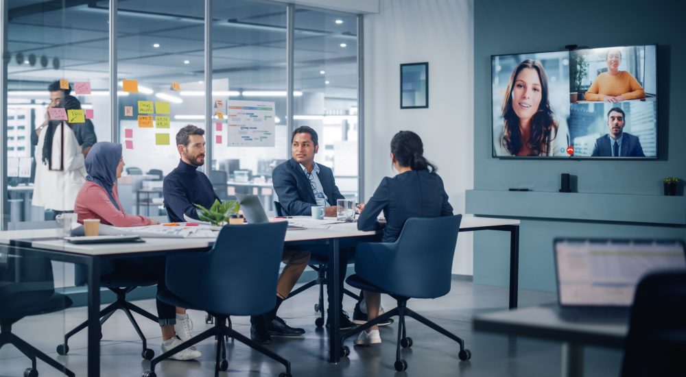 Businesspeople do Video Conference Call with Big Wall TV in Office Meeting Room. Diverse Team of Creative Entrepreneurs at Big Table have Discussion. Specialists work in Digital e-Commerce Startup