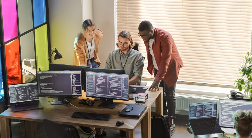 Male CEO and Female CTO Talking to Software Engineer Team Lead In Creative Office Space. Black Entrepreneur and Caucasian Business Partner Offering New Features For Their Innovative Online Service.